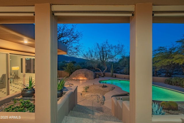 pool at dusk with a patio area