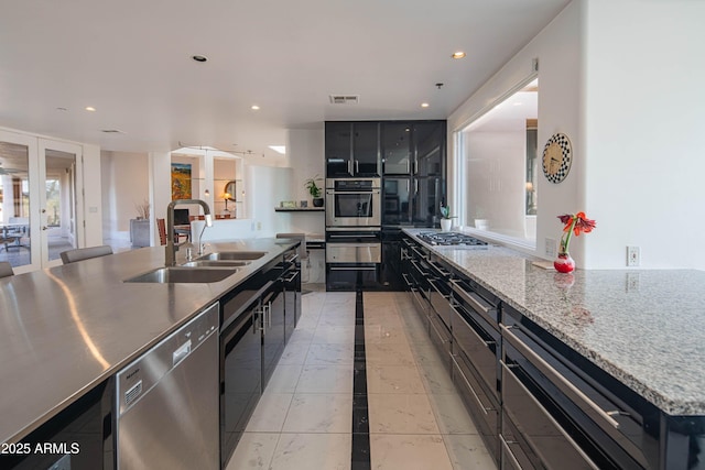 kitchen featuring sink, a center island, light stone counters, stainless steel appliances, and french doors