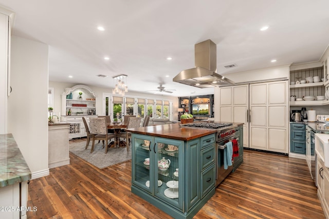 kitchen featuring wood counters, green cabinetry, high end stove, island range hood, and a ceiling fan