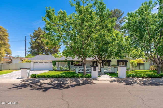 view of front of house featuring fence, decorative driveway, a front yard, and an attached garage
