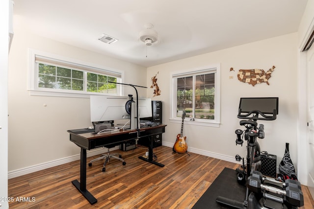 home office featuring wood finished floors, a ceiling fan, visible vents, and baseboards
