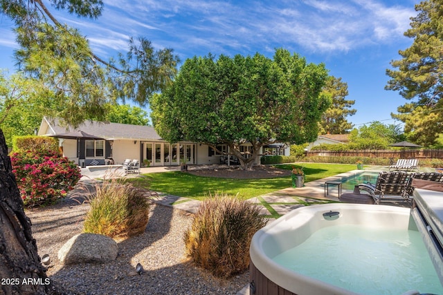 back of house with fence, a hot tub, a fenced in pool, a patio area, and french doors