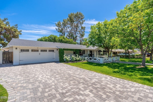 ranch-style house featuring fence, a front yard, decorative driveway, and an attached garage
