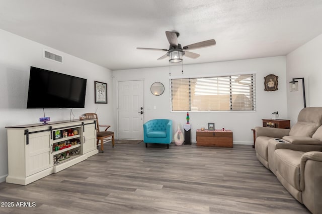 living room with ceiling fan, wood-type flooring, and a textured ceiling