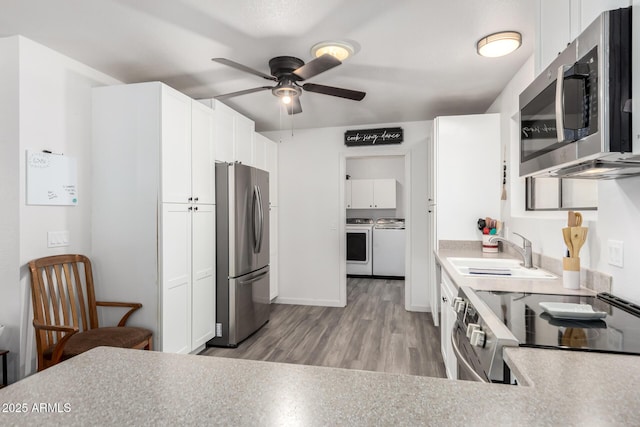 kitchen with appliances with stainless steel finishes, sink, washer and dryer, and white cabinets