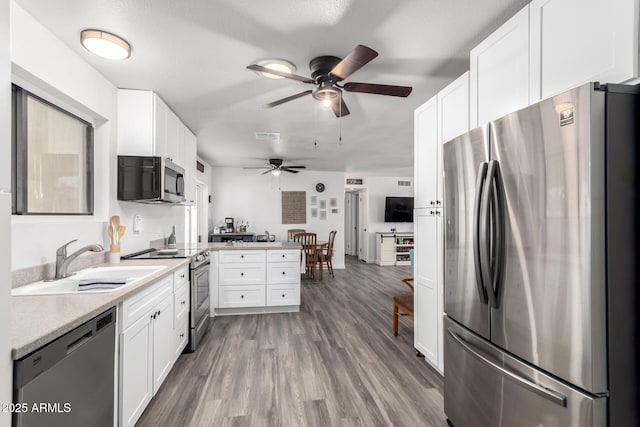 kitchen featuring stainless steel appliances, sink, wood-type flooring, and white cabinets