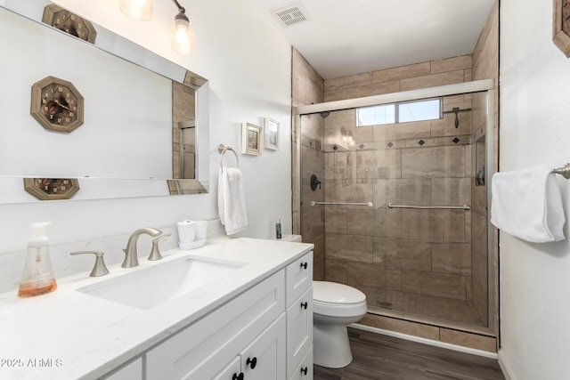 bathroom with an enclosed shower, vanity, wood-type flooring, and toilet