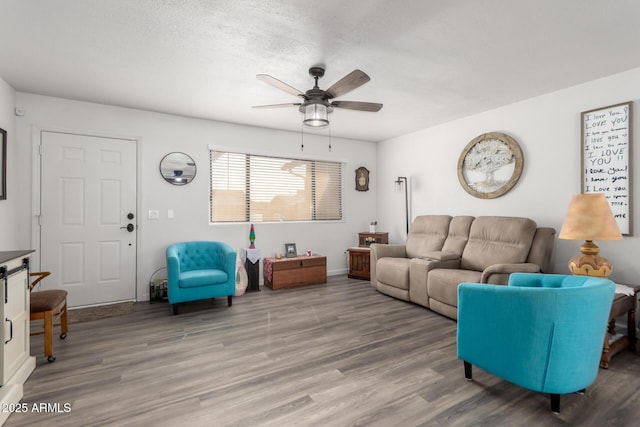 living room featuring hardwood / wood-style flooring, ceiling fan, and a textured ceiling