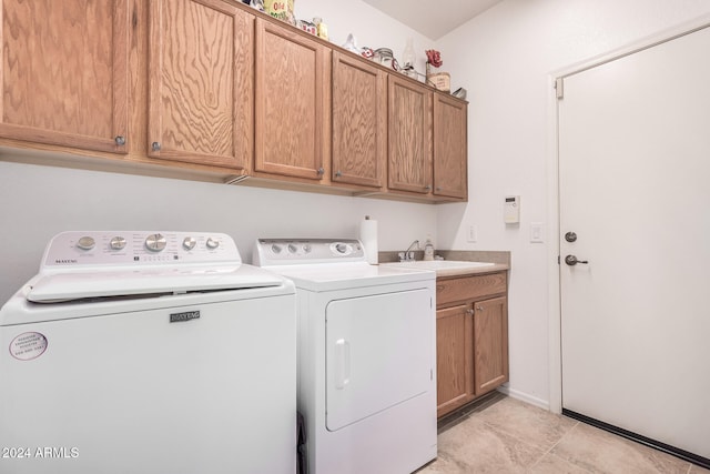 laundry area featuring cabinets, washing machine and dryer, light tile patterned floors, and sink