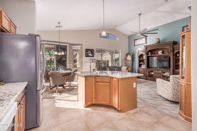 kitchen featuring pendant lighting, light stone counters, vaulted ceiling, and stainless steel refrigerator