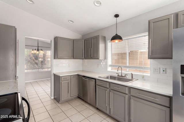 kitchen with light tile patterned floors, lofted ceiling, stainless steel appliances, gray cabinets, and a sink