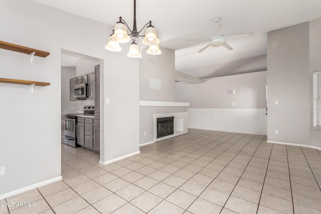 unfurnished living room featuring ceiling fan with notable chandelier, light tile patterned flooring, baseboards, and a tile fireplace