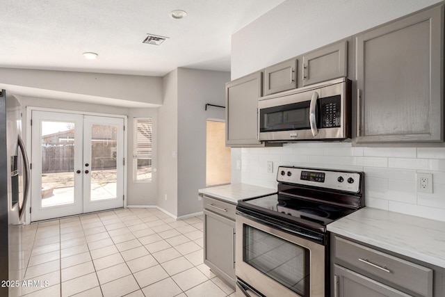 kitchen featuring appliances with stainless steel finishes, french doors, backsplash, and gray cabinetry