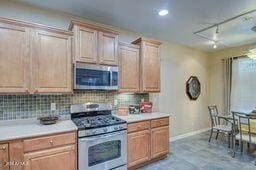 kitchen featuring light brown cabinetry, stainless steel appliances, and decorative backsplash