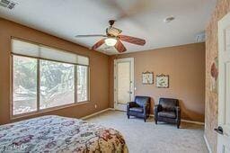 bedroom featuring ceiling fan, light carpet, and multiple windows