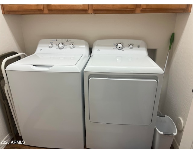 clothes washing area featuring washer and dryer and cabinets