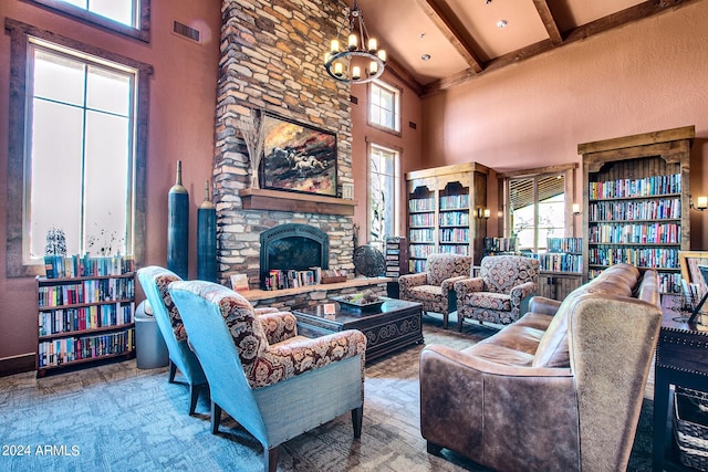 living room featuring beam ceiling, a stone fireplace, a high ceiling, and a chandelier