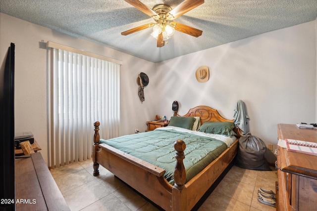 bedroom featuring ceiling fan, light tile patterned floors, and a textured ceiling