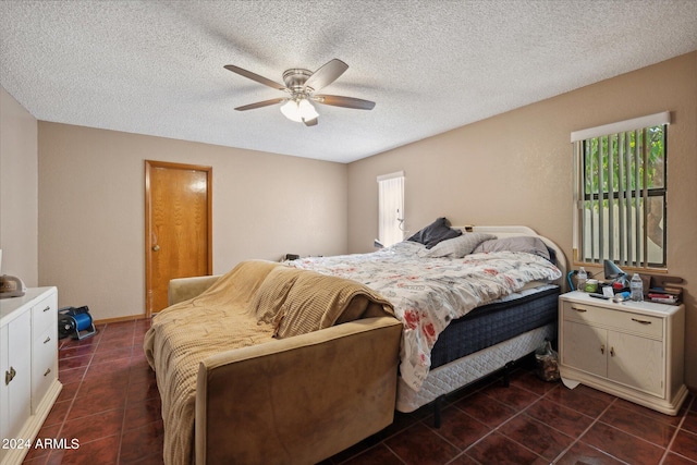 bedroom with dark tile patterned flooring, a textured ceiling, and ceiling fan