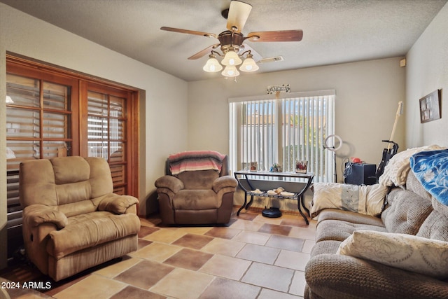 living room featuring ceiling fan and a textured ceiling