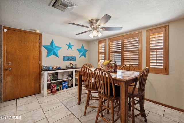 dining space featuring ceiling fan and a textured ceiling