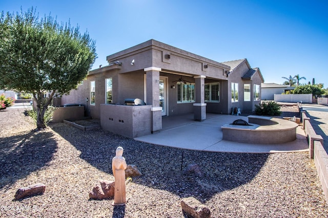 view of front facade with ceiling fan, a fire pit, and a patio area