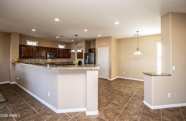 kitchen featuring light stone countertops, kitchen peninsula, hanging light fixtures, and stainless steel appliances