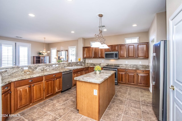 kitchen featuring a wealth of natural light, appliances with stainless steel finishes, a notable chandelier, and a kitchen island