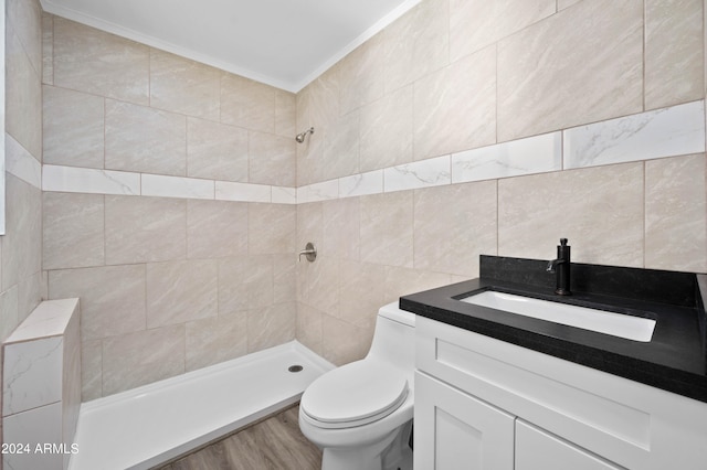 bathroom featuring crown molding, toilet, tiled shower, and vanity