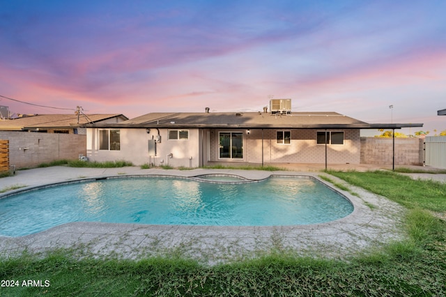 pool at dusk featuring an in ground hot tub and cooling unit