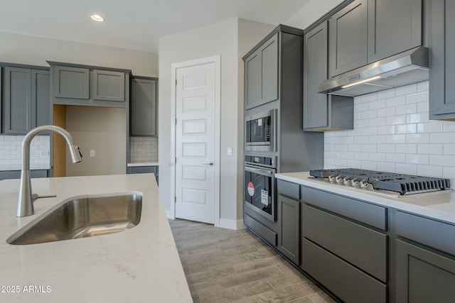 kitchen with stainless steel appliances, sink, gray cabinetry, and light stone counters