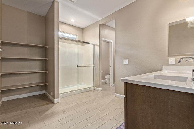 bathroom featuring vanity, toilet, wood-type flooring, and a shower with shower door