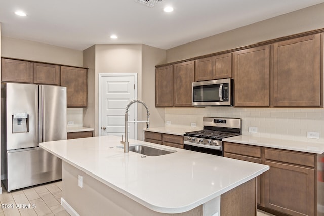 kitchen featuring decorative backsplash, sink, an island with sink, and stainless steel appliances