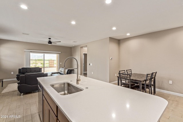 kitchen featuring sink, a kitchen island with sink, ceiling fan, stainless steel dishwasher, and light wood-type flooring