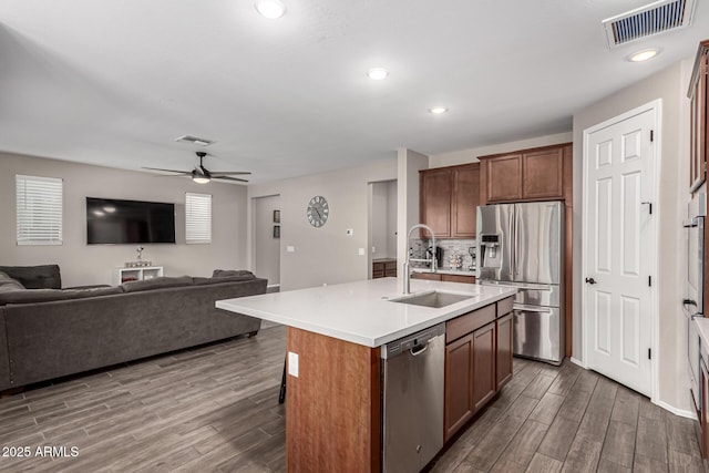 kitchen with dark hardwood / wood-style floors, sink, backsplash, a kitchen island with sink, and stainless steel appliances