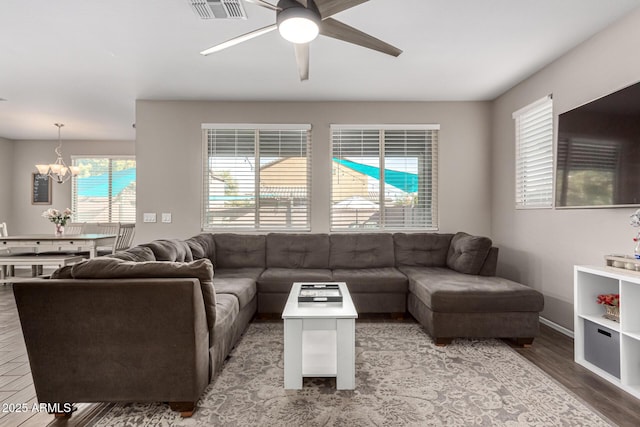 living room with ceiling fan with notable chandelier and hardwood / wood-style floors