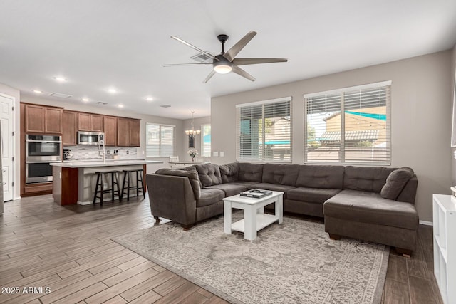 living room featuring hardwood / wood-style flooring and ceiling fan with notable chandelier