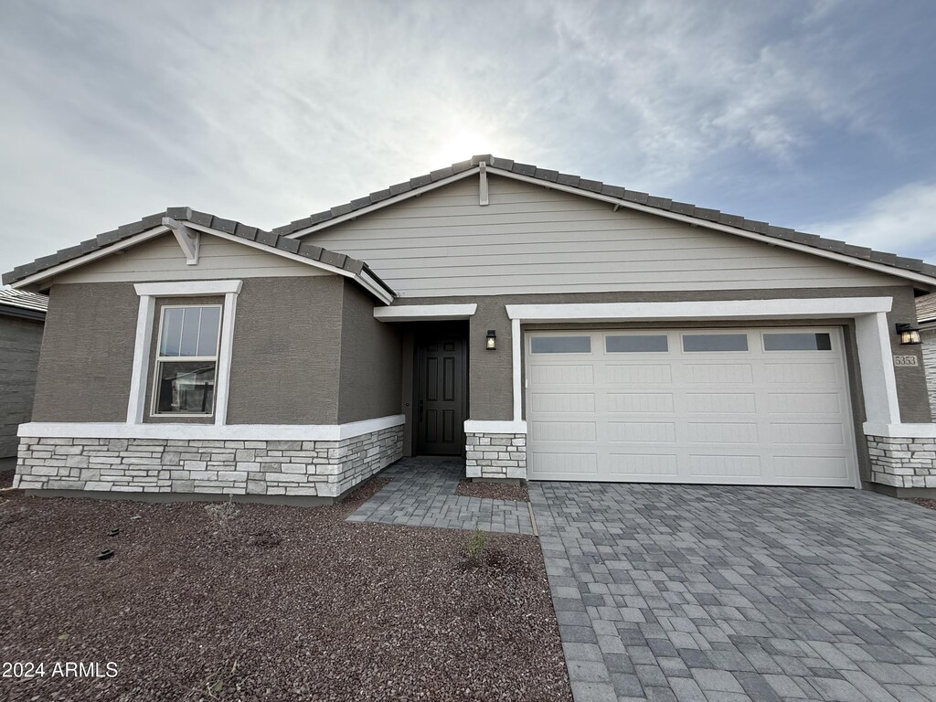 view of front of house featuring stone siding, driveway, and an attached garage