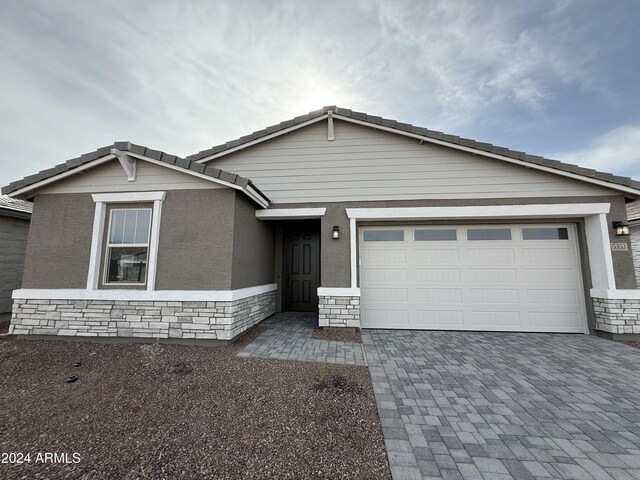 view of front of house featuring stone siding, driveway, and an attached garage