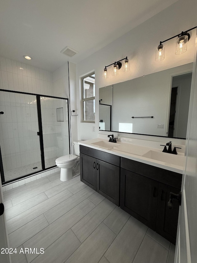 bathroom featuring vanity, toilet, and a shower with shower door