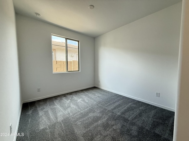 spare room featuring dark colored carpet