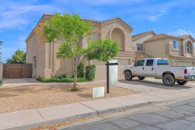 mediterranean / spanish-style house with concrete driveway, stucco siding, a gate, and a garage