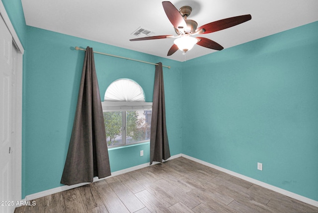 unfurnished room featuring baseboards, ceiling fan, visible vents, and wood finished floors