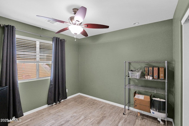 spare room with baseboards, a ceiling fan, wood finished floors, and visible vents