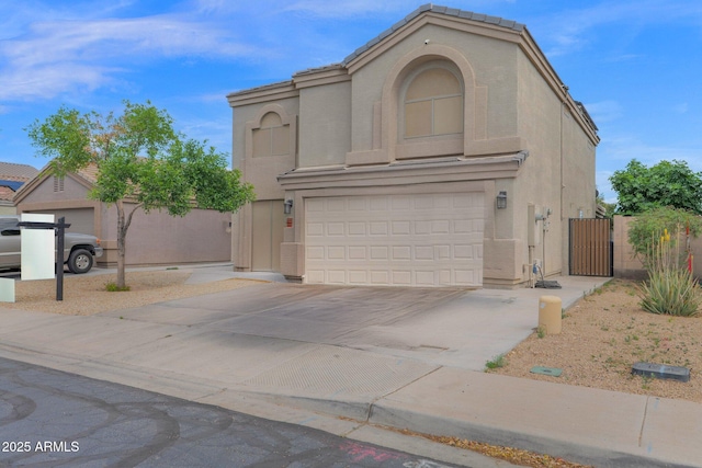 view of front of property with a gate, an attached garage, driveway, and stucco siding
