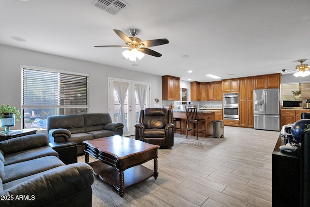 living room featuring visible vents, light wood-style floors, recessed lighting, french doors, and a ceiling fan