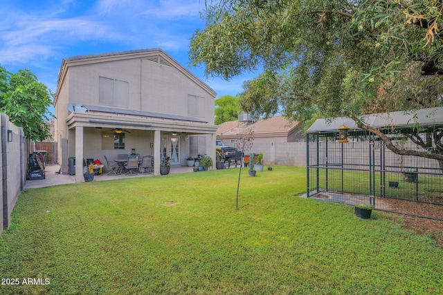 back of property featuring ceiling fan, a fenced backyard, stucco siding, a patio area, and a lawn