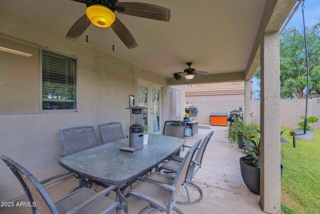 view of patio / terrace with a ceiling fan, fence, french doors, and outdoor dining space