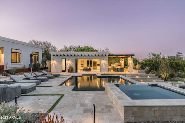 pool at dusk featuring an outdoor hangout area, an in ground hot tub, and a patio area