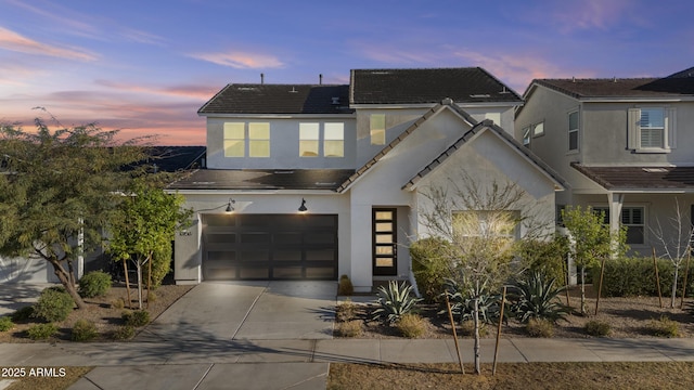 view of front facade with driveway, solar panels, stucco siding, a garage, and a tile roof